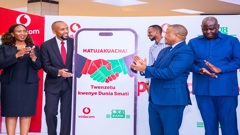 Top executives from Vodacom Tanzania and CRDB Bank, Philip Besiimire (2nd from L) and Abdulmajid Nsekela (2nd from R) respectively, applaud at the event held in Dar es Salaam.