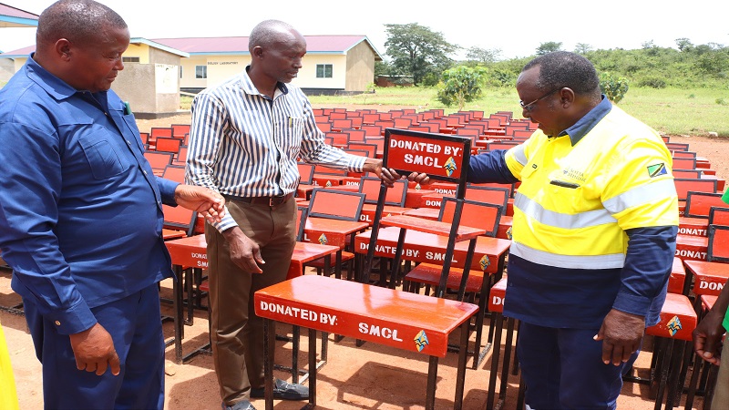 Nyang’hwale District acting education officer Jonathan Rwezaula (C) receives 160 desks and chairs from Sotta Mining Company Ltd community relations manager John Bwana (R) earlier this week. 
