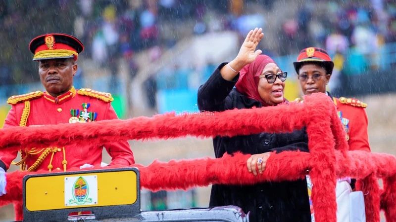 President and Commander-in-Chief Samia Suluhu Hassan arrives at Uhuru Stadium in Dar es Salaam yesterday, waving to the thousands of people who braved daylong rain to attend celebrations to mark the 60th anniversary of the Union of Tanganyika and Zanzibar