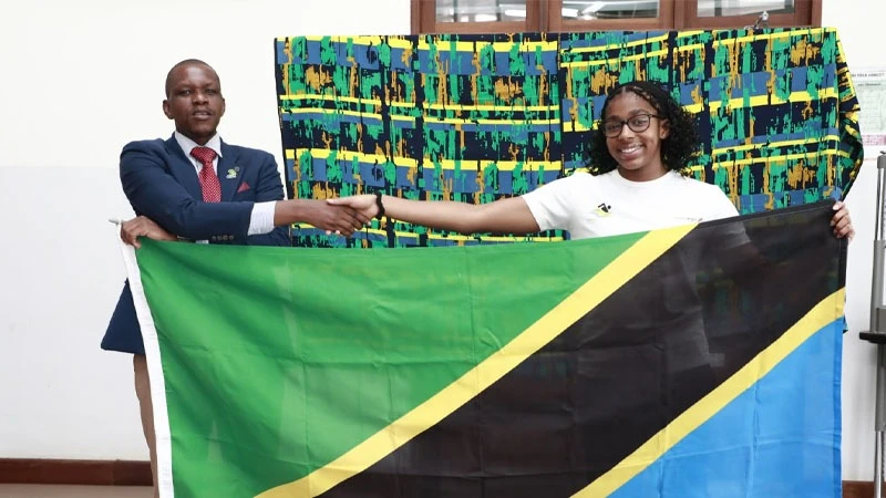 National Sport Council's Sports Officer Charles Maguzu (L) hands over the national flag to Tanzania's national swimming team captain Sophia Latiff ahead of their flight to Angola to battle it out in the African Swimming and Open Water Championships. 