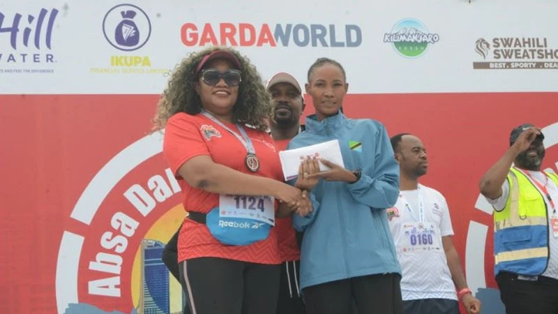 
Head of Retail Banking for Absa Bank Tanzania, Ndabu Lilian Swere (L), presents a prize to the first-place winner of the half marathon (21km) in the Absa Dar City Marathon for women, Sara Ramadhani from Arusha.