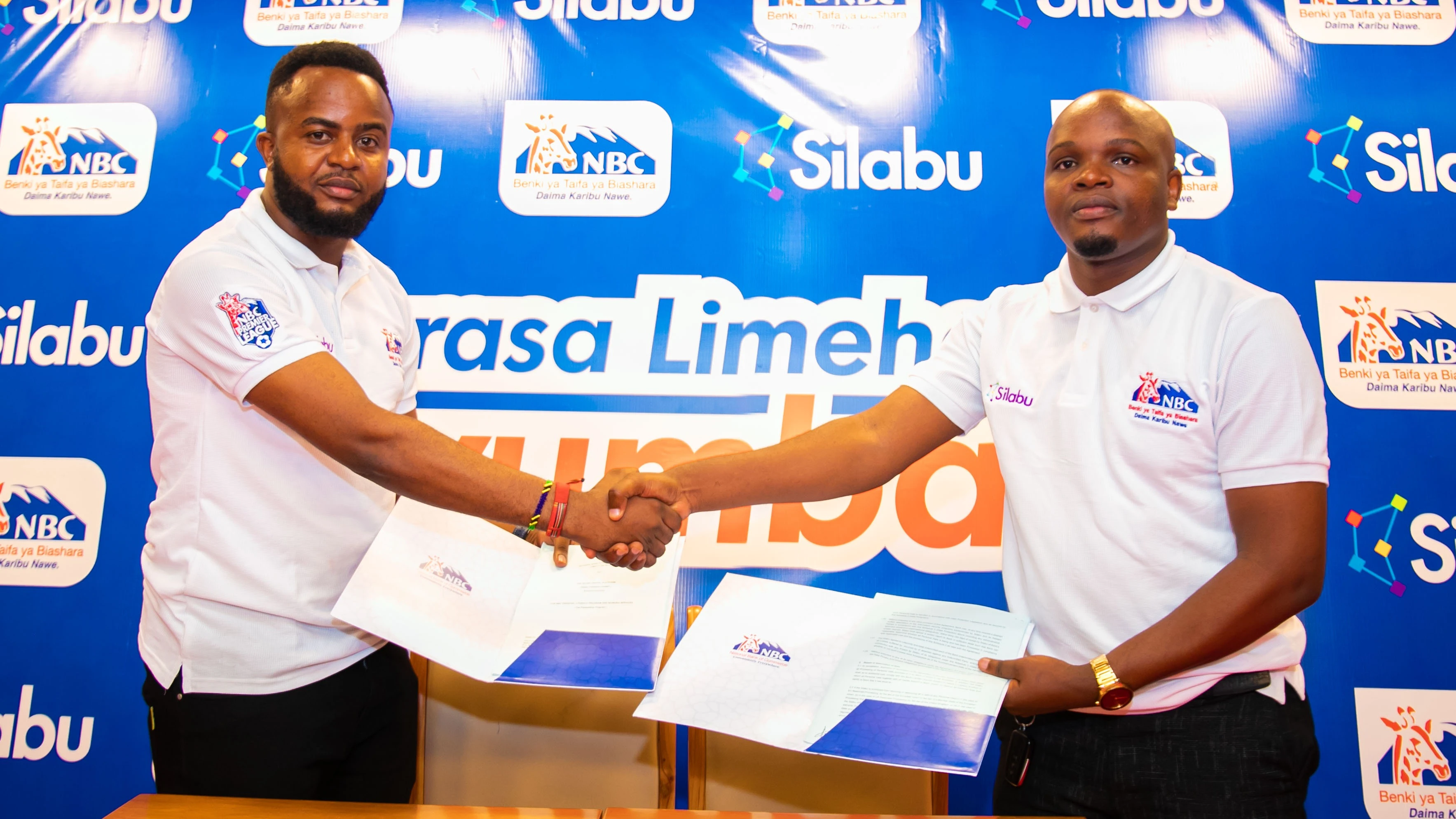NBC's Education Services Manager, Yoabu Ndanzi  (R), and Adam Duma, Co-founder of SILABU APP, a company that provides supplementary education  (tuition) services for pupils and students at home and through the internet, congratulate each other .