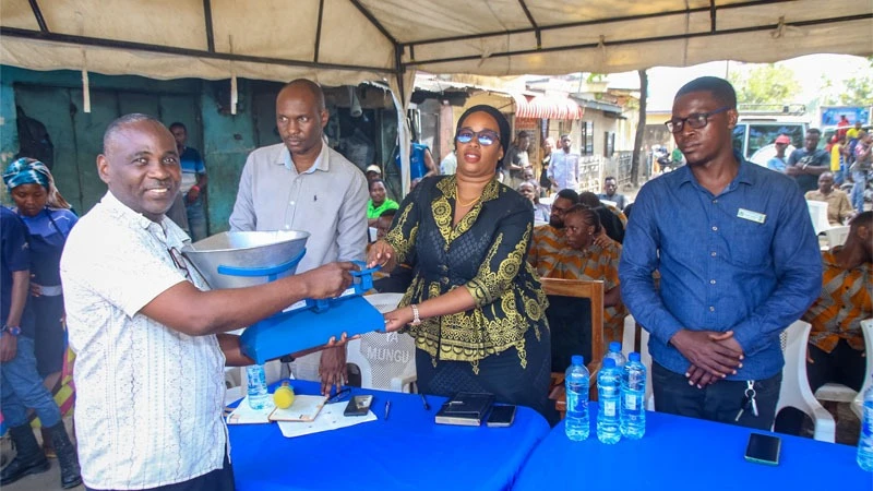 Charangwa Selemani (2nd – R), Ilala district administrative secretary, presents a weighing machine to Ali Mbiku, Ilala market chairperson, at the World Measurement Day commemoration. Accompanied by Muhono Nashon (2nd - L), WMA Ilala regional manager.