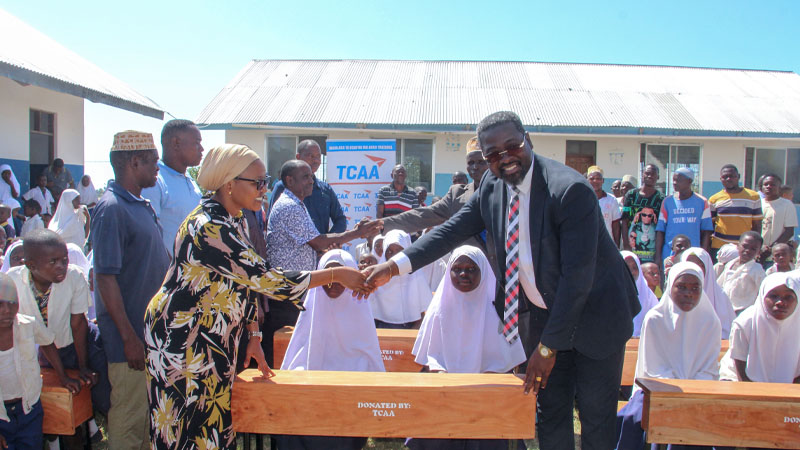  Yessaya Mwakifulefule, the Tanzania Civil Aviation Authority (TCRA) communication manager, presents a donation of school items to Mtwara DC Mwanahamisi Munkunda for use by Mnete primary school, yesterday. 