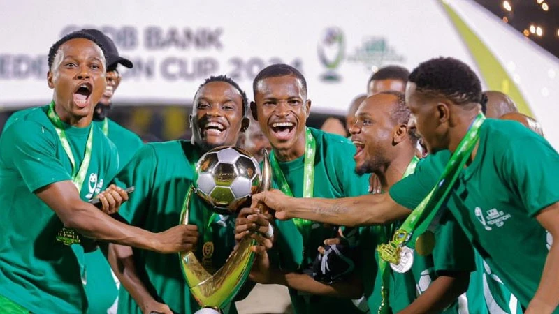 Young Africans SC players celebrate with the trophy after winning the Federation Cup final match against Azam FC at the New Amaan Complex in Zanzibar on Sunday. Young Africans won after the penalty shootout 6-5