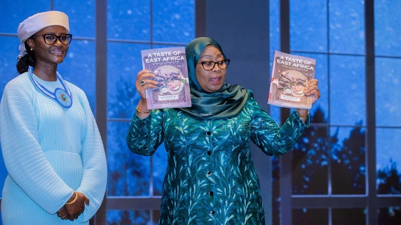 President Samia Suluhu Hassan pictured in Seoul on Wednesday brandishing copies of ‘A Taste of East Africa’. It was shortly after she launched the book, authored by Chaba Mavura (L), at an event attended mainly by Tanzanians living in South Korea