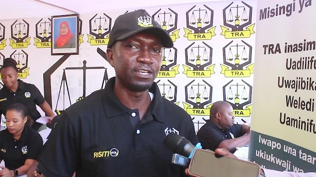 Caption: Flavian Babyato, TRA Principal Tax Supervisor of the Tanga region, engages with visiting journalists at his pavilion during the 11th TCCIA Tanga Trade Fair.