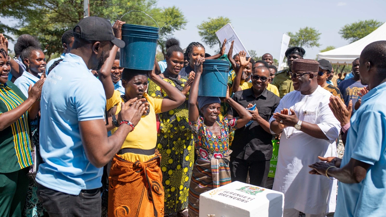 Mwanza Regional Commissioner, Said Mtanda (Right) and the Managing Director of Serengeti Breweries, Obinna Anyalebechi carrying buckets of water to the women of Kabila village to mark the launch of the rural water project there.
