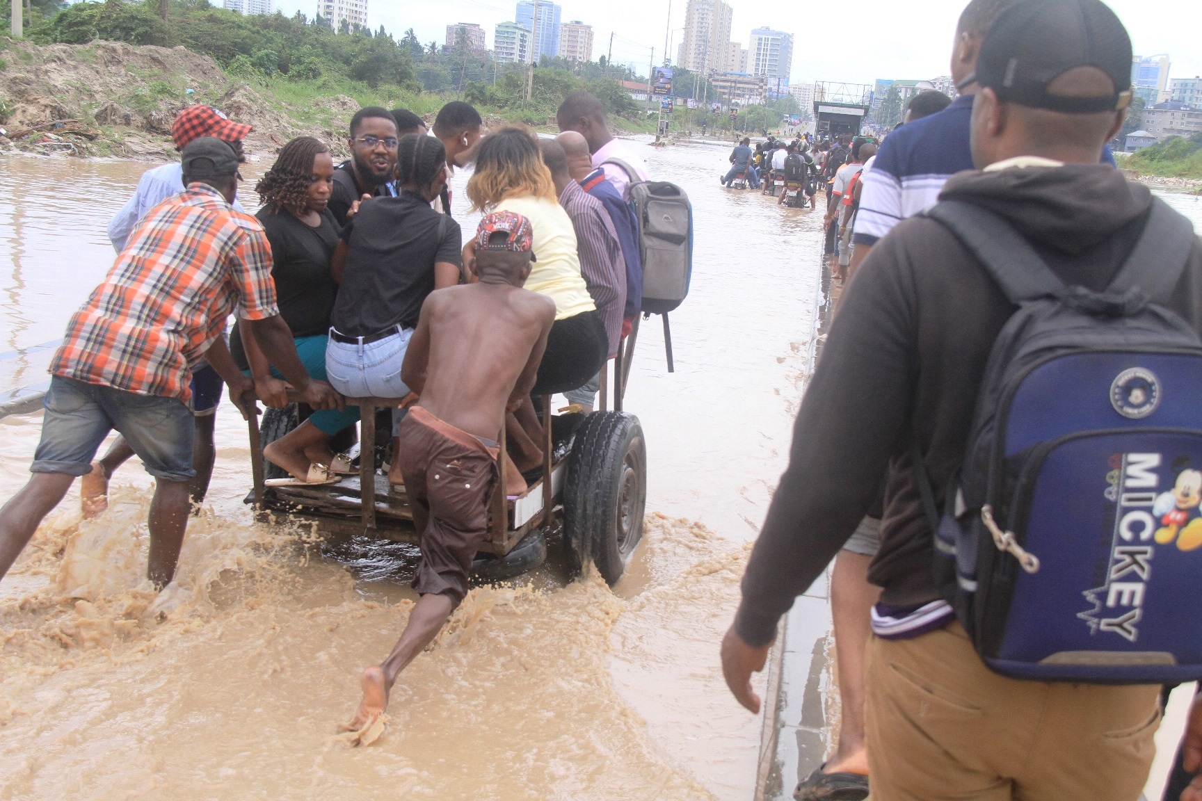 Some Dar es Salaam residents climb into a cart to cross Jangwani Bridge following heavy rain early yesterday.