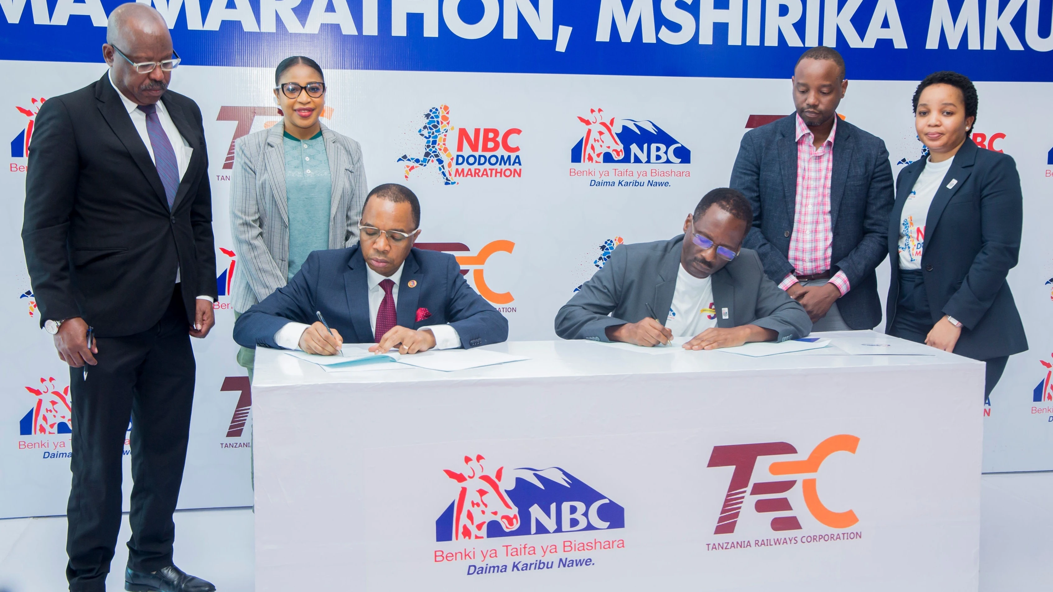 Mkurugenzi Mkuu wa Shirika la Reli Tanzania (TRC), Masanja Kadogosa (kushoto) na Mkurugenzi wa Fedha wa Benki ya NBC, Waziri Barnabas (kulia) wakisaini makubaliano ya ushirikiano wa kiutendaji baina ya taasisi hizo mbili.