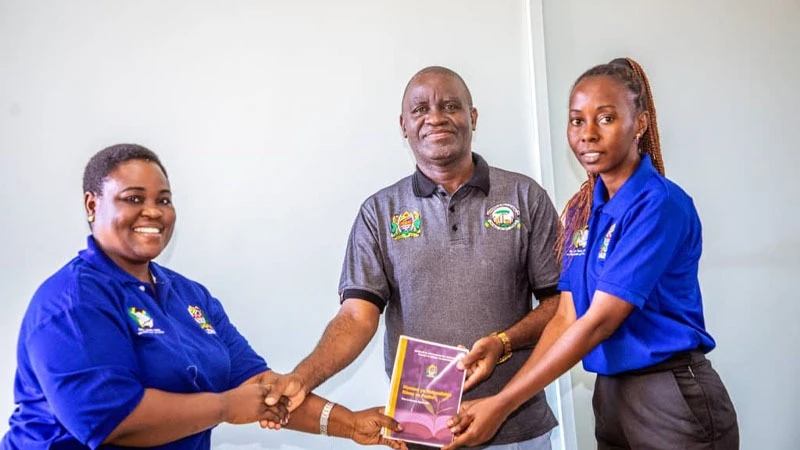 
Sikonge District Executive Director, Seleman Pandawe (C) receives a book with various topics including investment, savings, and loans that will be used to provide financial education to people in the district from Limi Bulugu,