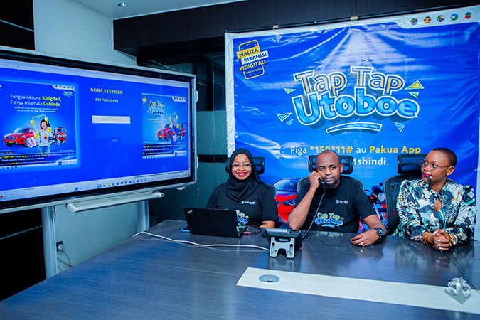 Silas Matoi (center), Head of Alternative Digital Channels at Exim Bank Tanzania, speaking with one of the 10 winners of the second draw of the Tap Tap Utoboe campaign aimed at encouraging the bank's customers to use mobile phones and the internet for pay