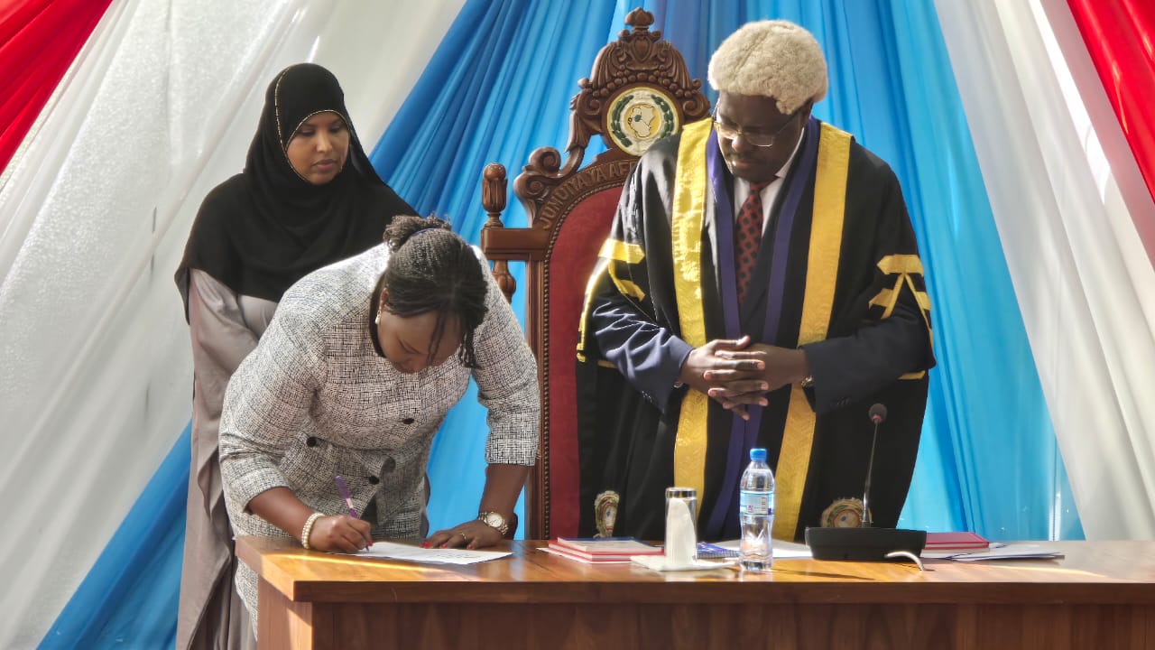 Veronica Nduva, the new East African Community (EAC) secretary general, signs the oath shortly after being sworn in by the East African Legislative Assembly (EALA) Speaker Joseph Ntakirutimana (R) as a member in Arusha on Tuesday. 