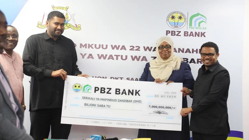 Zanzibar Minister of State- President's Office (Finance and Planning) Dr. Saada Mkuya Salum (2nd R) receives a dummy cheque worth 7bn/- from the People's Bank of Zanzibar (PBZ)  Managing Director, Arafat Haji (L) as a dividend for the year 2023.