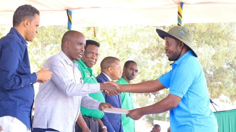 
Deputy Prime Minister Doto Biteko hands over a laptop to Rashid Sikwala, the Manager cum Secretary of Muloku Amcos Ilolangulu Uyui district in Tabora region, as the Minister of Agriculture Hussein Bashe (L) witnesses. 