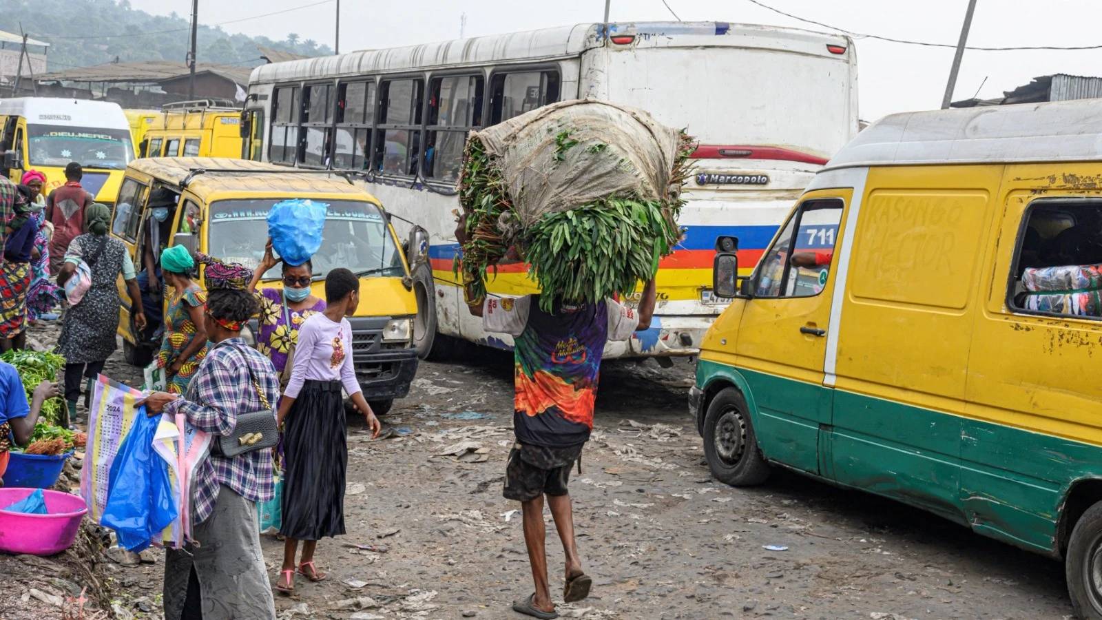 A boy balances a bundle of kasava leaves as he navigates traffic in Kinshasa, on July 2, 2024. 