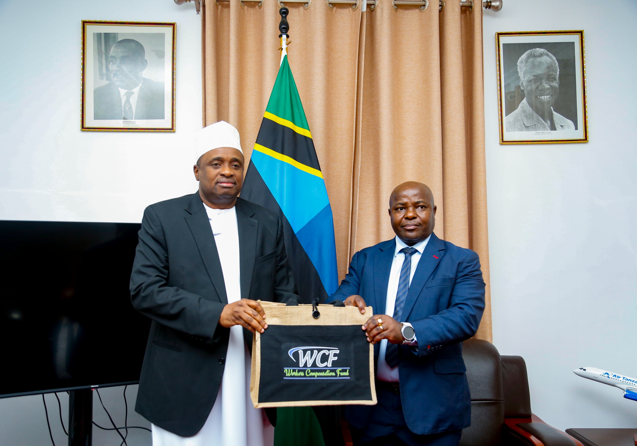 Zanzibar Second Vice President Hemed Suleiman Abdulla (L) receives documents from Workers Compensation Fund director general Dr John Mduma in Zanzibar yesterday shortly after witnessing the signing of an MoU on cooperation between WCF and the ZSSF.