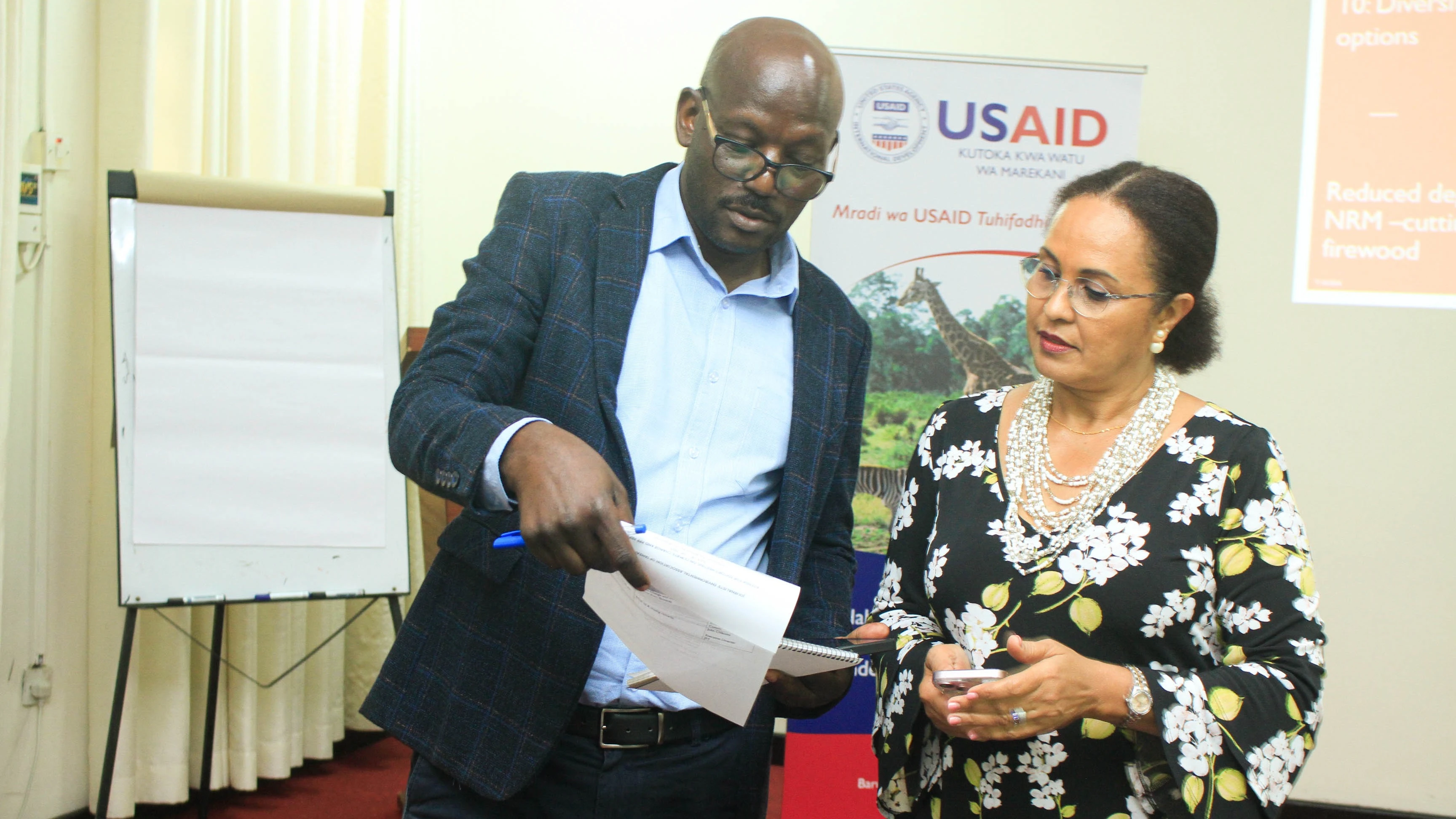 Dr. Elikana Kalumanga, Private Sector Engagement Manager for RTI (a USAID contractor implementing the Tuhifadhi Maliasili project (L) discusses with the Environmental Journalist Association (JET) board chairperson Dr Ellen Otaru (R ) .