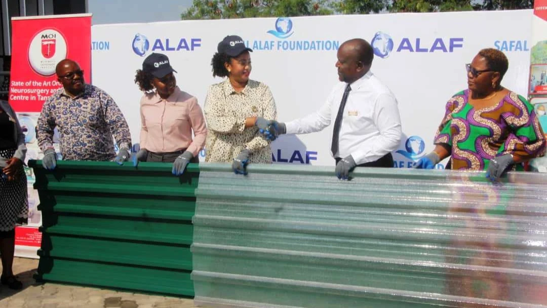 ALAF Limited Tanzania external affairs officer Theresia Mmasy (C) pictured in Dar es Salaam yesterday presenting to Muhimbili Orthopaedic Institute (MOI) acting managing director Dr Antony Assey a consignment of corrugation iron roofing sheets worth 35m/-
