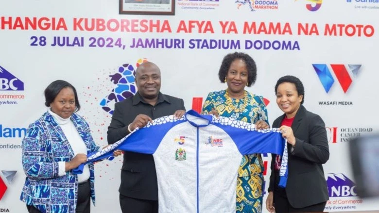 The Dodoma Regional Commissioner, Rosemary Senyamule (2nd R), receiving a special NBC Dodoma Marathon jacket from the Head of Communications and Public Relations at NBC Bank Godwin Semunyu (2nd Lt) and the Chairperson of the Marathon Organizing Committee,