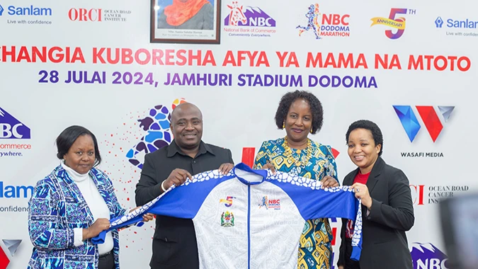 Mkuu wa Mkoa wa Dodoma, Rosemary Senyamule  (wa pili kulia) akipokea sweta maalum la mbio za NBC Dodoma Marathon kutoka kwa Mkuu wa Kitengo cha Mawasiliano na Mahusiano ya Umma wa Benki ya NBC, Godwin Semunyu (wa pili kushoto).