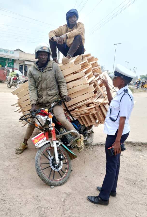 Police Traffic Officer, Sergeant Selina Manda, educates a 'Bodaboda' rider on road safety after arresting him for carrying luggage and a passenger in Mapinda, Sengerema Town.