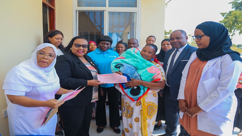 Constitution and Legal Affairs minister Dr Pindi Chana (2nd-L) presents a birth certificate to a baby’s mother while touring Kikuyu Health Centre in Dodoma city at the weekend to assess progress in the ongoing registration of under-fives. 