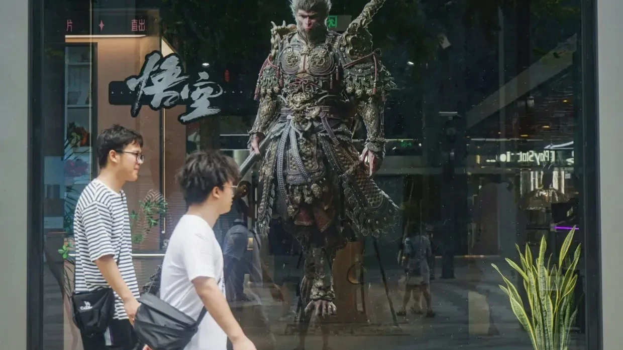 People walk past the image of the "Monkey King" character, or "Sun Wukong" of the Chinese action role-playing game "Black Myth: Wukong", developed by Chinese video game company Game Science, during its launch day in Hangzhou, in Eastern China's Zhejiang