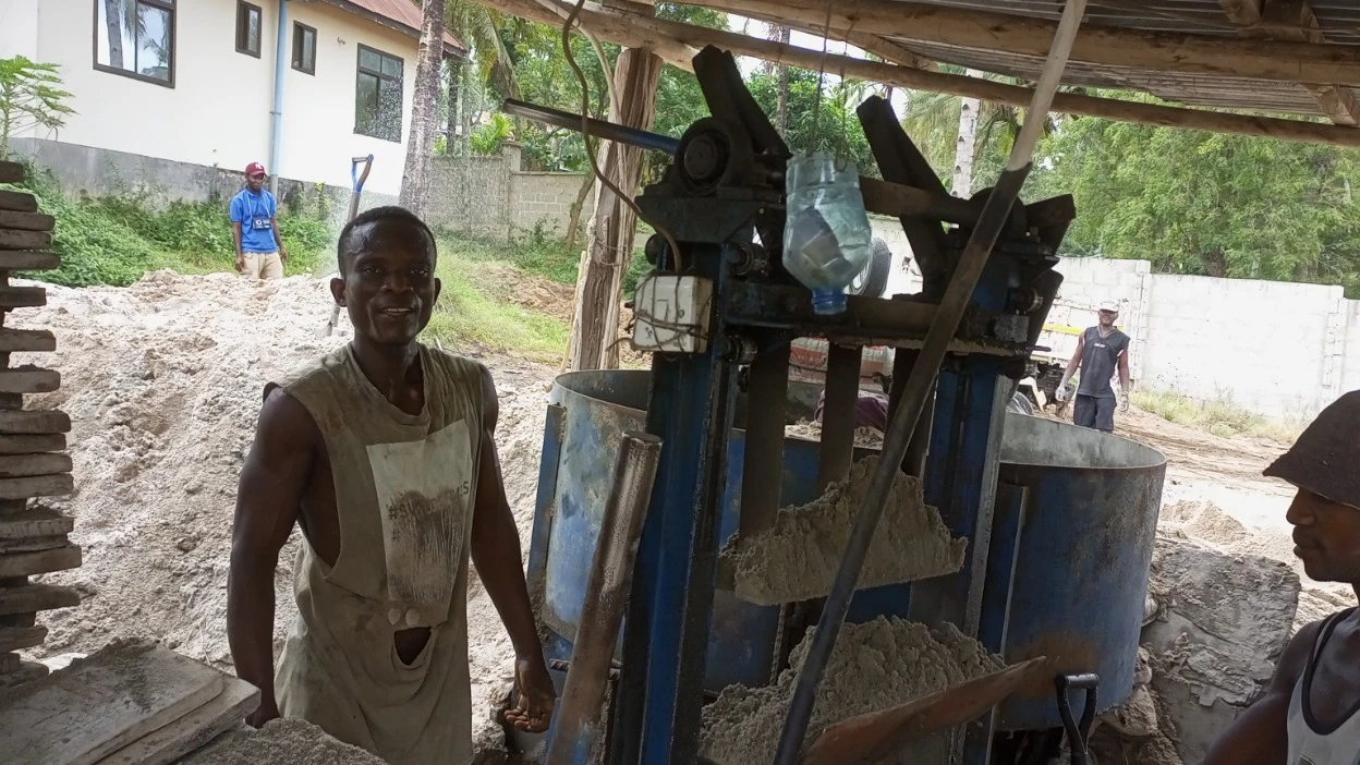 Moses Mwingwa (38) works as the mortar operator without protective gears. Assisting him is Erasto Kubindi (41).
