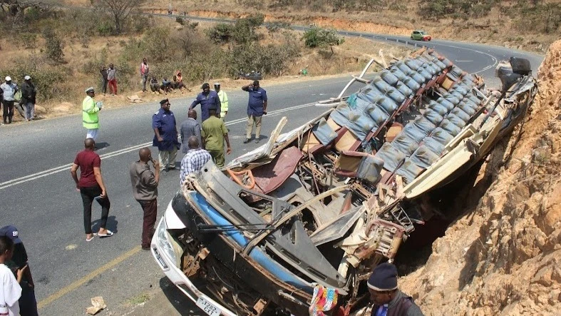 Traffic police officers pictured yesterday at the spot where a commuter bus (see wreckage) was involved in road crash at Lwanjilo village in Mbeya District yesterday, leaving 12 people dead and 36 injured. 