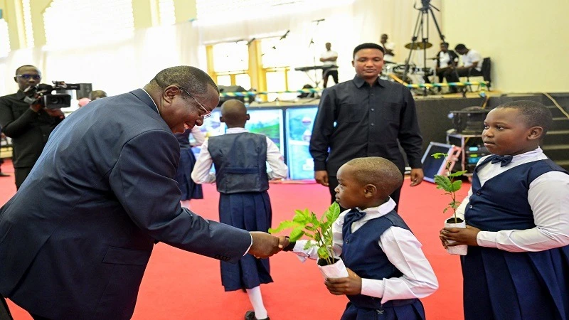 Vice President Dr Philip Mpango congratulates pupils of Dodoma’s Mnadani Primary School on their spectacular performance in the singing of an environmental conservation song at a meeting held in the city yesterday. 