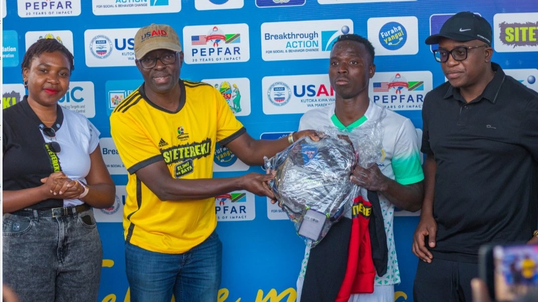 Moses Bateganya, a USAID representative (2nd L) awards Kassim Hussein who was named the player of the match during the opening of Ndondo Cup tournament in Dodoma between Kikuyu FC and Nkuhungu Terminal FC. 