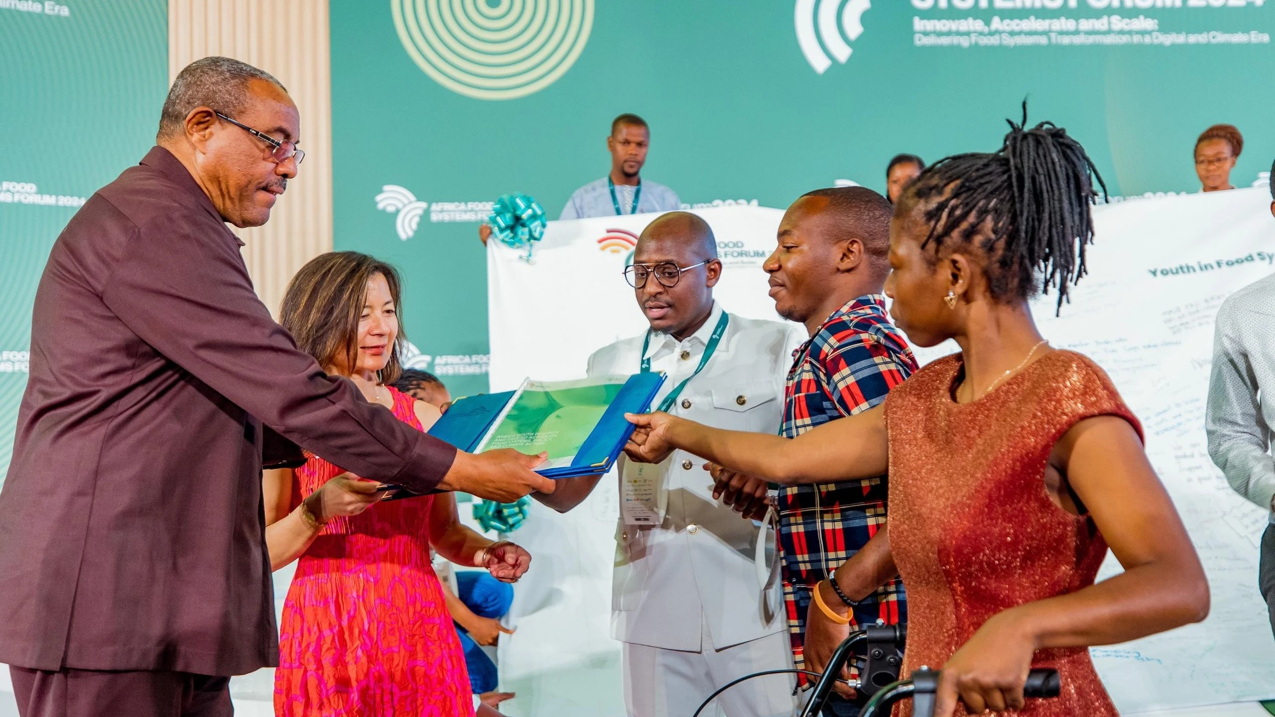 
AGRA Board Chair Hailemariam Dessalegn (L) , Mastercard Foundation CEO Reeta Roy (2nd L) receive a copy of the Kigali Declaration on Food Systems, Policy and Climate Action from differently abled youth from Malawi and Mozambique.