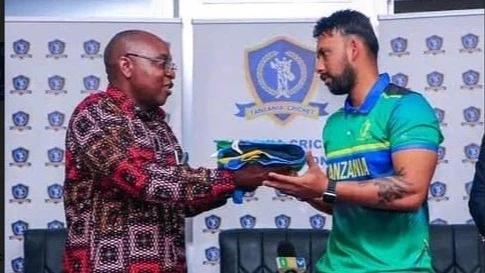 Minister for Culture, Arts, and Sports Damas Ndumbaro (L) is pictured handing over the national flag to Tanzania's men's cricket team skipper Abhik Patwa at an occasion in Dar es Salaam last week.