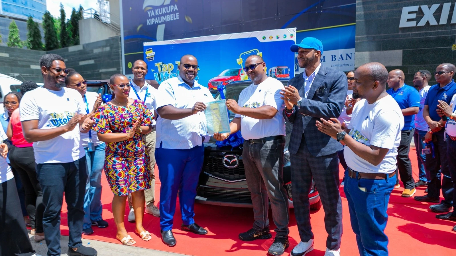 The grand prize winner of Exim Bank’s ‘Tap Tap Utoboe’ campaign, Geofrey Muganyizi (third from left), proudly receives the keys to a brand-new Mazda CX-5 from Andrew Lyimo, Head of Retail and SME Banking at Exim Bank. Also present at the handover ceremony