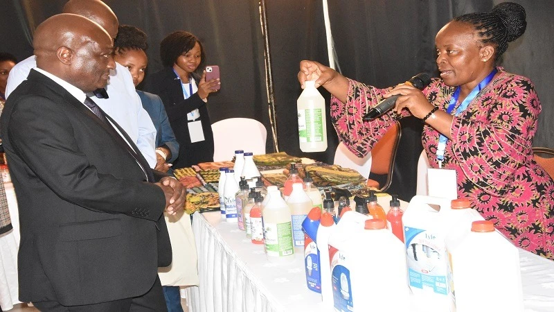 The Deputy Permanent Secretary of the Ministry of Industry and Trade, Dr. John Simbachawene,  (L ) admires products made by one of entrepreneur who attended the launch of the Small Industries Day organised by TASSIM