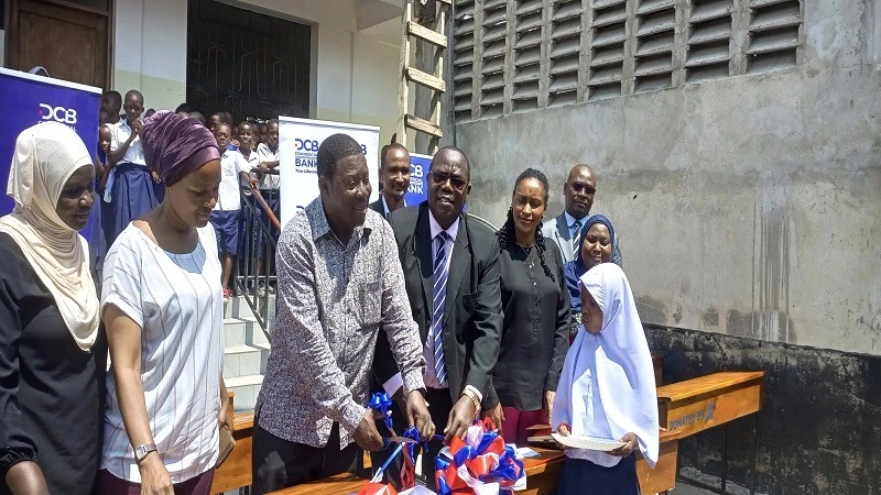 Songoro Mnyonge, Mayor of Kinondoni Municipality cuts a ribbon to symbolise the handing over of 30 desks donated by DCB Bank for Msisiri ‘B’ primary school yesterday in Dar es Samaa. 