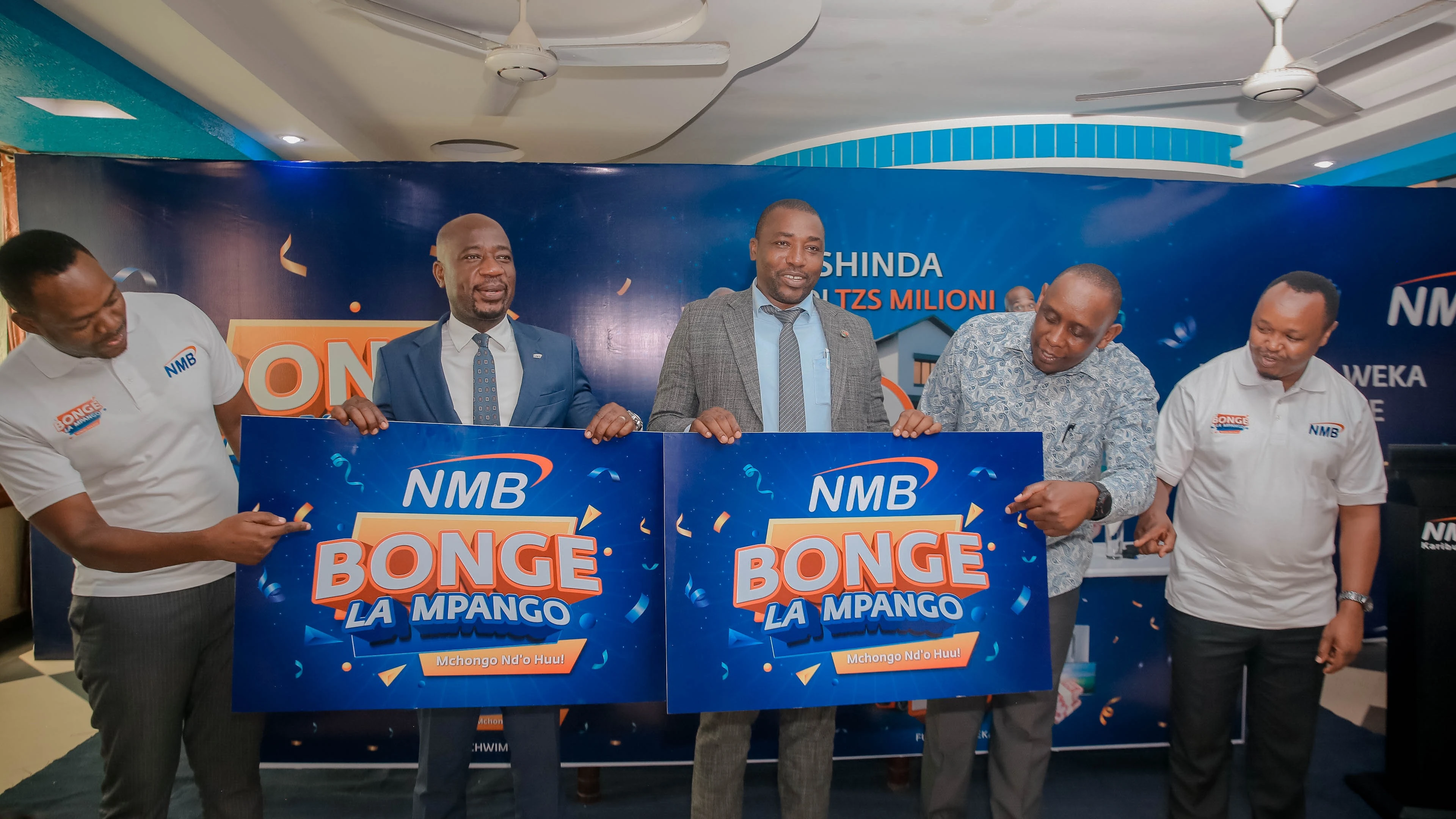 Dar es Salaam Regional Administrative Secretary, Dr. Toba Nguvila (C) and NMB Bank’s Chief of Retail Banking, Filbert Mponzi (2nd L)  hold banners of the three months campaign dubbed: “Bonge la Mpango” shortly after launching it in Dar es Salaam