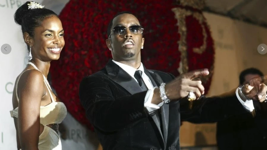 FILE - Sean “P. Diddy” Combs directs photographers as they sing “Happy Birthday,” to him as his date Kim Porter, left, listens, after Combs arrived for his 35th birthday celebration at Cipriani on Wall Street in New York, Nov. 4, 2004.