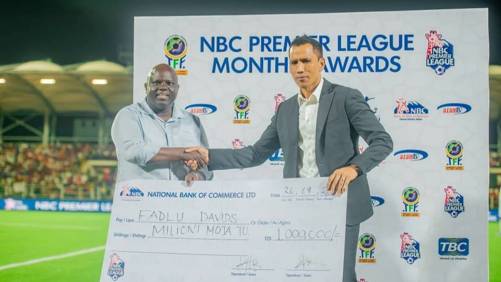 Mwenyekiti wa Chama Cha Soka Mkoa wa Dar Es Salaam (DRFA) Lameck Nyambaya (Kushoto) akikabidhi hundi yenye thamani ya sh milioni moja  kwa kocha mkuu wa klabu ya SC Fadlu Davids alietangazwa kocha Bora wa Ligi Kuu ya NBC kwa mwezi Agosti.