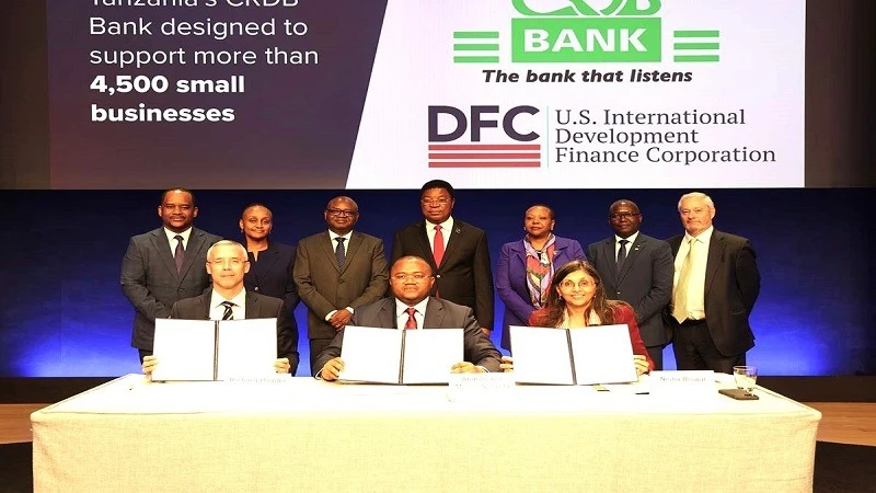 Prime Minister Kassim Majaliwa (C, standing) and the Minister of State in the President’s Office Planning and Investment), Prof Kitila Mkumbo (3rd-L, standing), and senior officials of CRDB Bank, the US International Development Finance Corporation (DFC) 