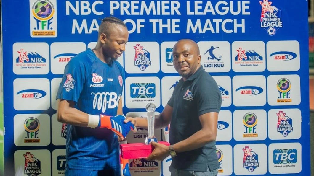 NBC Bank’s Zanzibar Branch Business Development Manager, Obedy Ngavatula (R), handing over the 'Man of the Match' award to Simba SC goalkeeper, Moussa Camara, who was announced the 'Man of the Match' during the recent ‘Mzizima Derby’