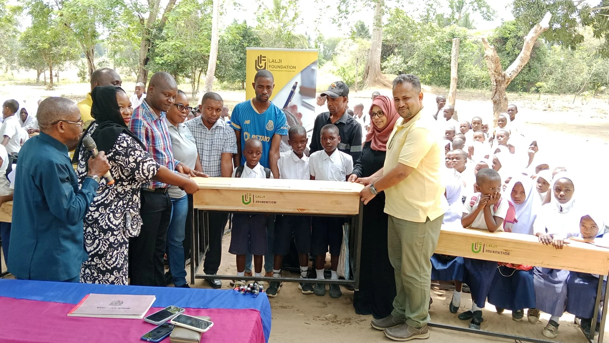 Mohamed Damji, Vice Chairman of the Lalji Foundation(right)  hands over desks to Kisarawe District Council Chairman, Zuberi Kizwezwe(nd left)  during an event held in Kisarawe District, Coast Region.