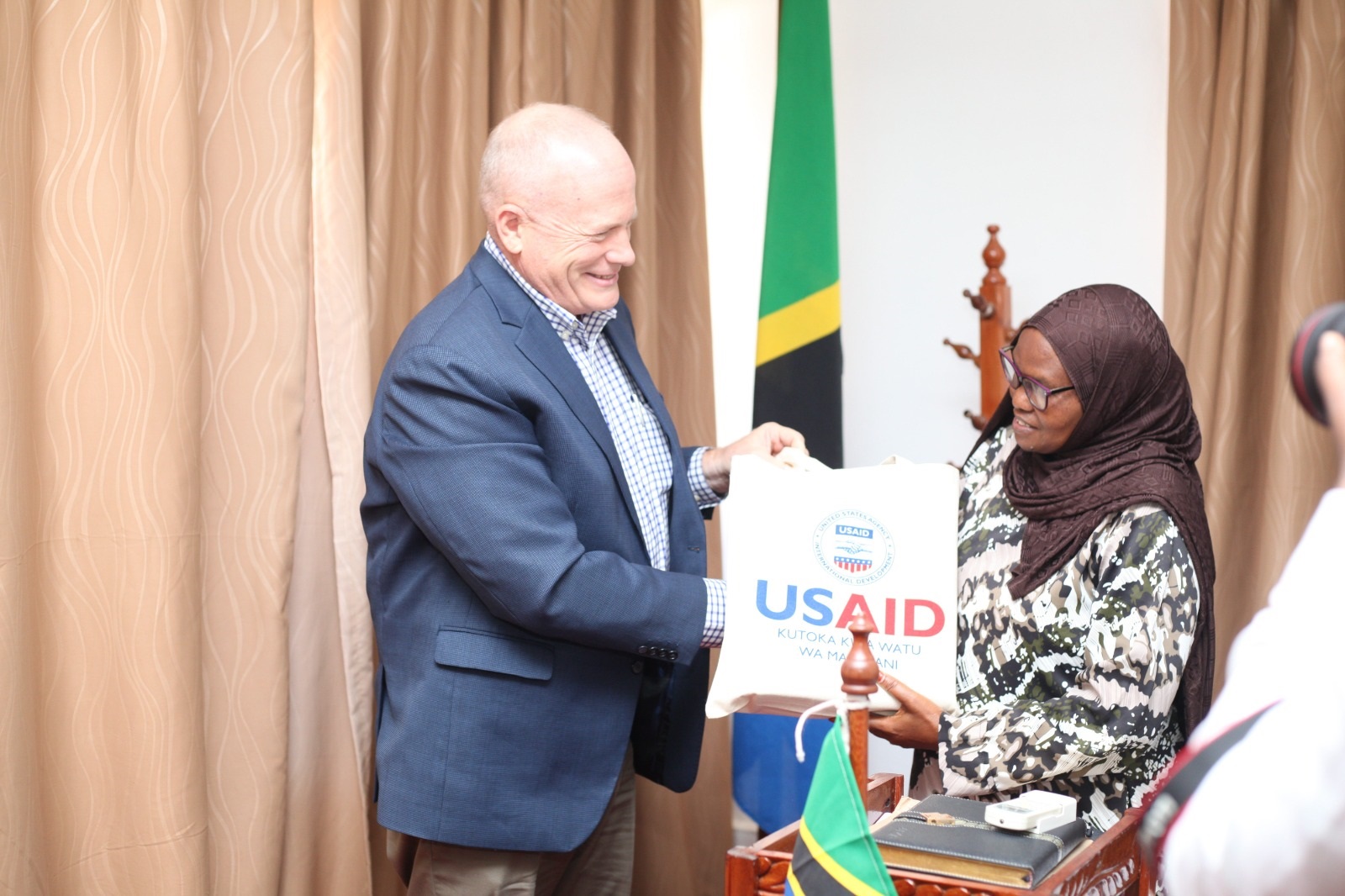 USAID Mission Director for Tanzania Craig Hart hands over assorted items to Lindi Regional Commissioner Zainabu Telack during his visit in the region to inspect programmes funded by the agency. 