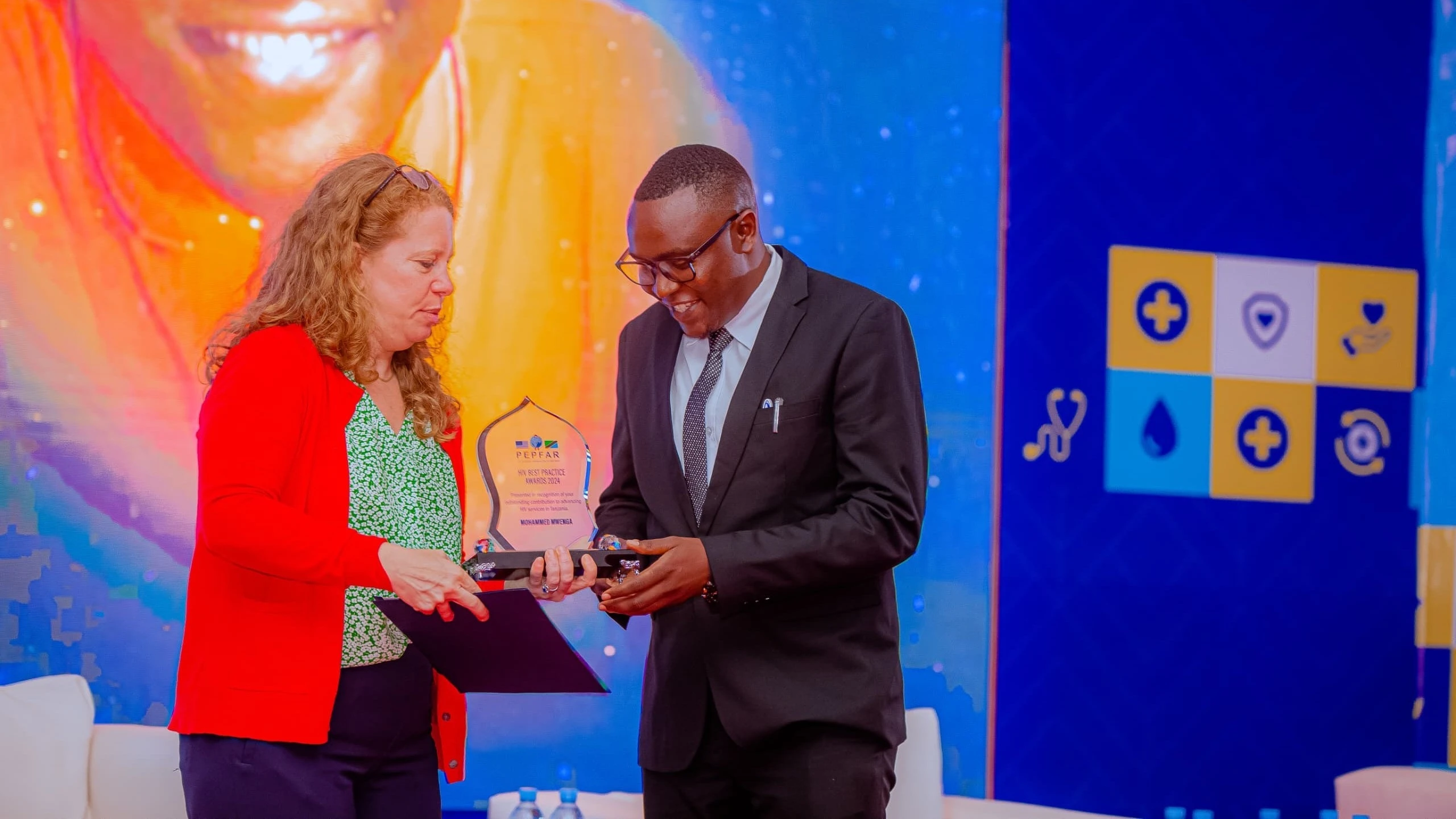 Mohamed Mwenga (R), senior social behaviour change advisor with a USAID health project in southern Tanzania, pictured in Zanzibar at the weekend receiving the 2024 PEPFAR HIV best practice award from PEPFAR Country coordinator Jessica Greene. 