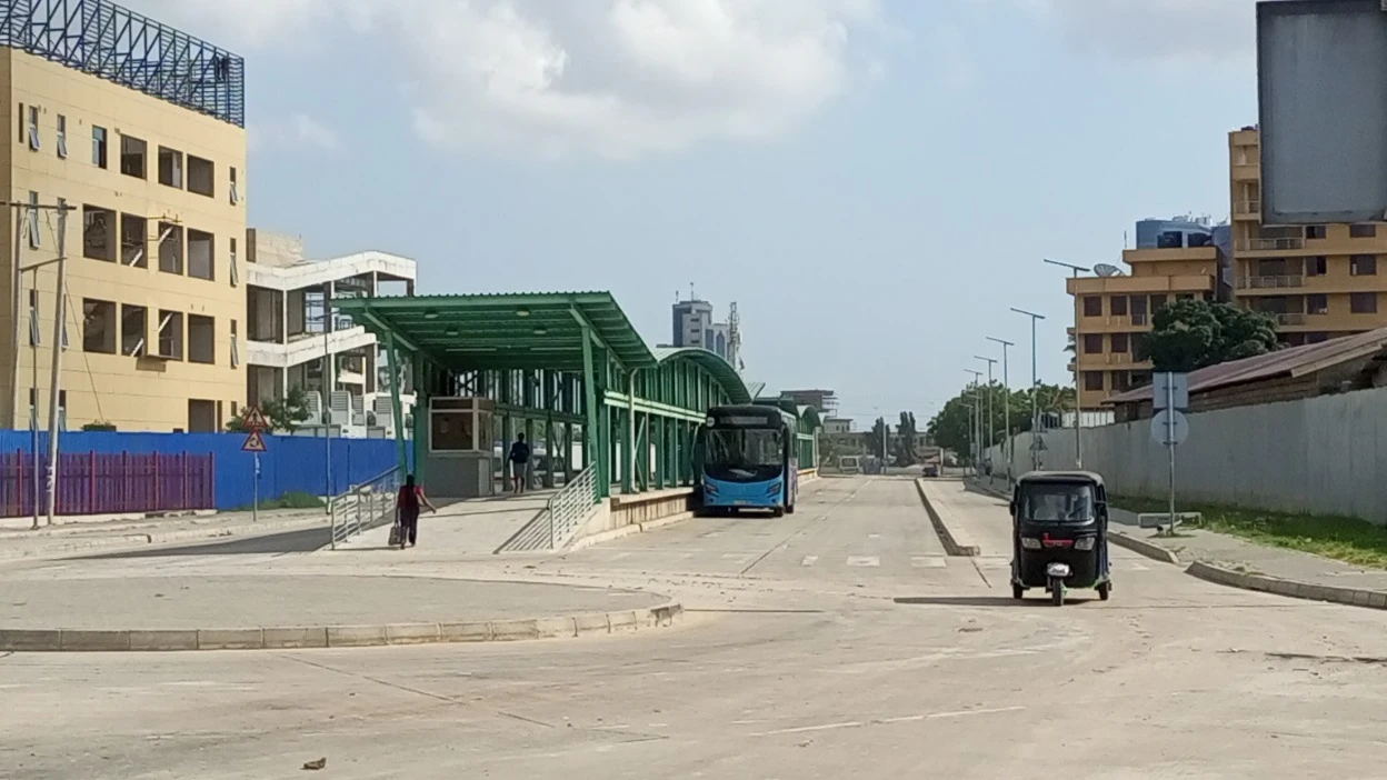 A bus rapid transit station in Dar es Salaam between ongoing construction projects on either side of the station without a space for roadside vegetation. 