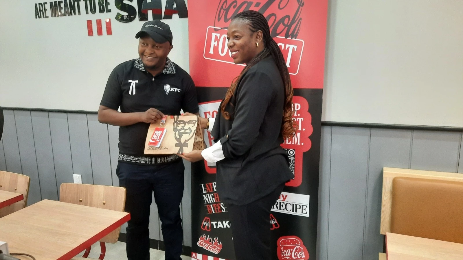 Kabula Nshimo (left), Senior Marketing Manager of Coca-Cola Tanzania, and Shafii Abbas Idege, Operations Lead at KFC Tanzania, showcase a sample of the food pass during the launch of a new loyalty program in Dar es Salaam. 