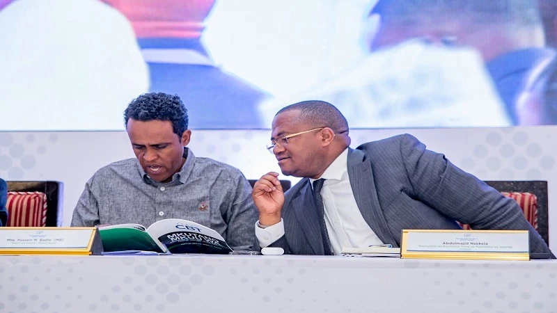 Minister of Agriculture, Hussein Bashe (L), discusses with the Chairman of the Tanzania Commission for Development of Cooperatives and CRDB Bank CEO, Abdulmajid Nsekela, during the inaugural Annual General Meeting of the Cooperative Bank of Tanzania (CBT)