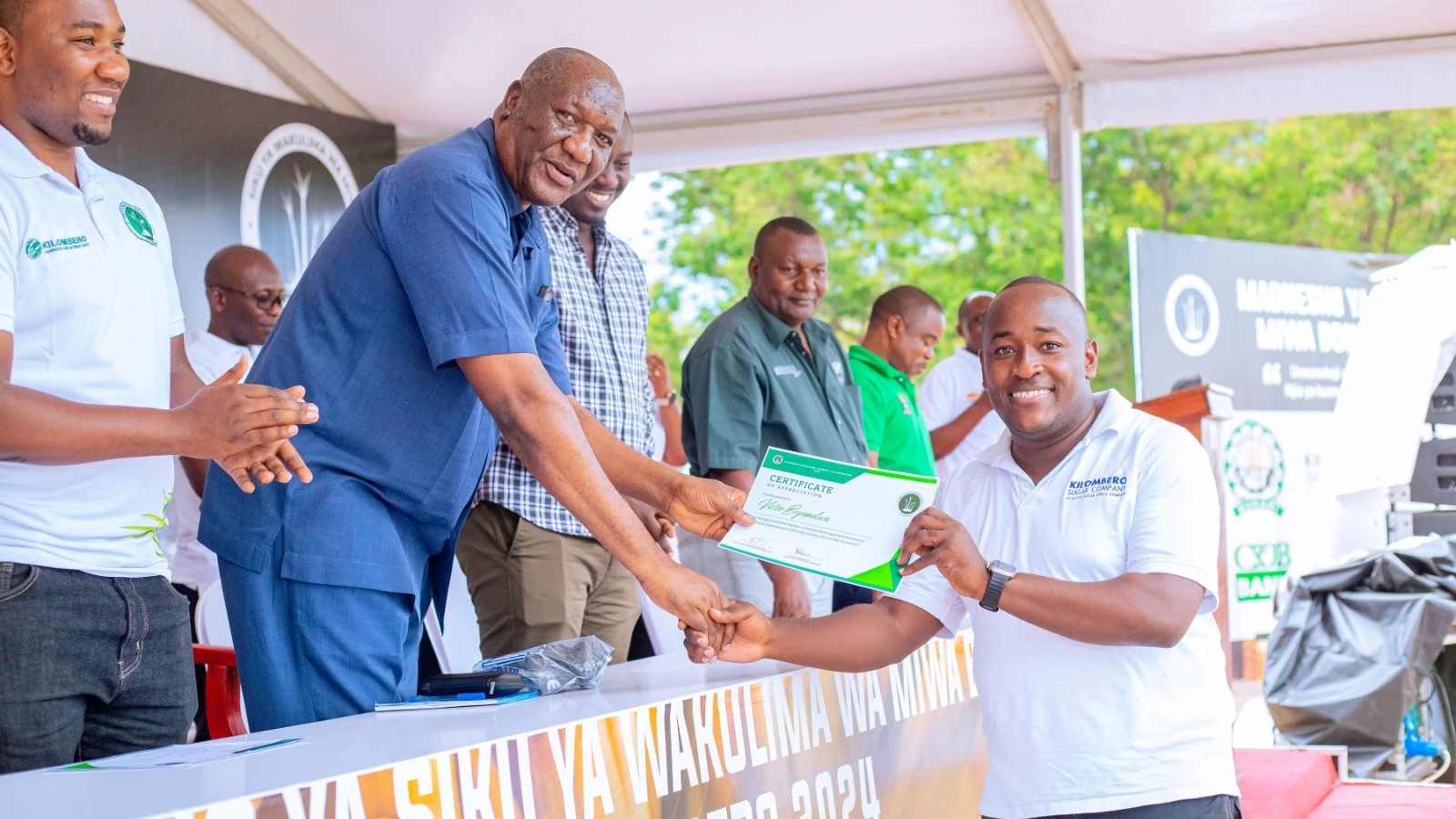 Victor Byemelwa, Chairman of the Kilombero Sugarcane Farmers' Day exhibition and Communications and Stakeholder Relations Manager at Kilombero Sugar receives a recognition certificate from the SBT Director General Prof Kenneth Bengesi.