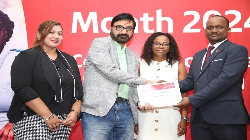 Absa Bank Tanzania, Managing Director, Obedi Laiser (R), hands over a certificate of appreciation to the vice president of Mohamed Enterprises Tanzania Limited (MeTL), Vipul Kakad (2nd L) during a ceremony to conclude the bank's customer service week.